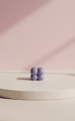 Peach wax candle with shimmering pink pearl bubble top in a low clear glass cup