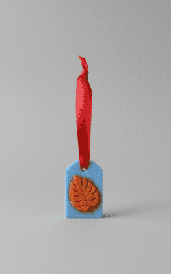 Hanging wax room freshener with blue base, orange leaf emboss and red ribbon