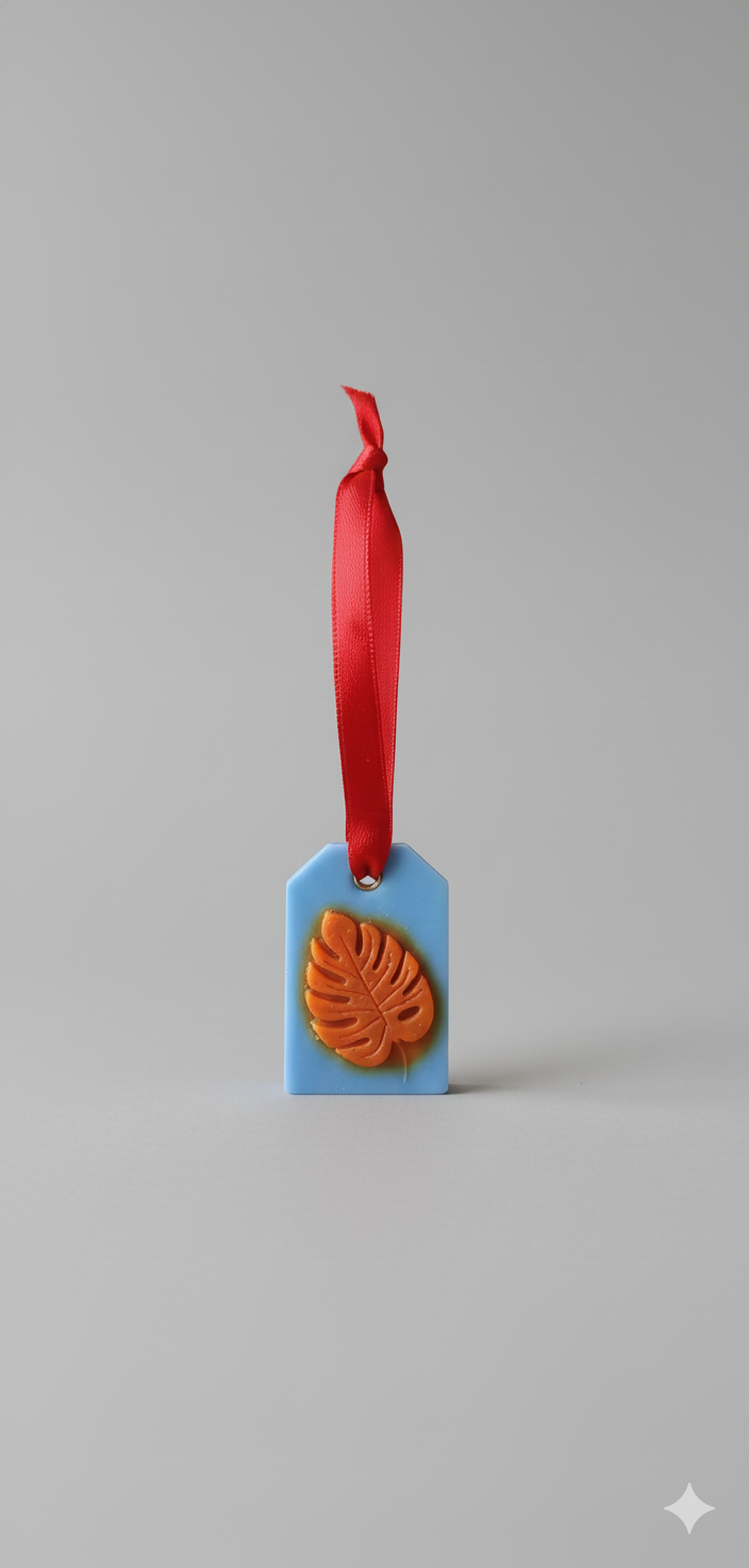 Hanging wax room freshener with blue base, orange leaf emboss and red ribbon