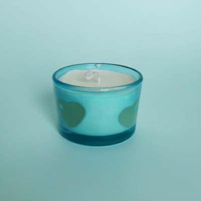 “Blue frosted glass candle with cream wax and embedded heart-shaped wax designs”