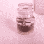 “Jar candle with brown wax base and transparent gel layer containing cinnamon sticks and cloves”