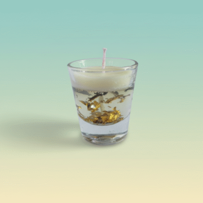 “Transparent gel and cream wax scented candle with floating gold flakes in a clear glass cup”