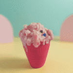 Pink ice cream cup–style scented wax candle with whipped cream-like top and sprinkles