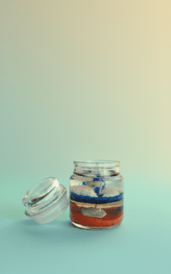 Ocean-themed blue gel wax candle with embedded seashells and cream wax layer in a glass jar