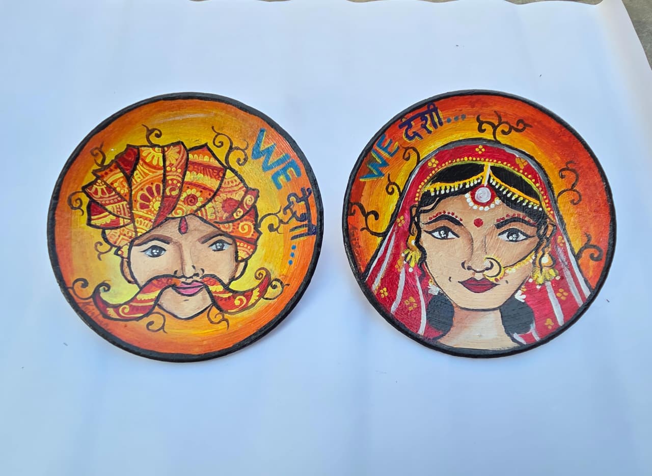 “Hand-painted Rajasthani bride and groom terracotta wall plates with orange-yellow gradient background”