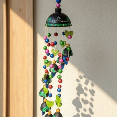 “Handcrafted black and green terracotta wind chime with colourful beads and bells hanging outdoors”