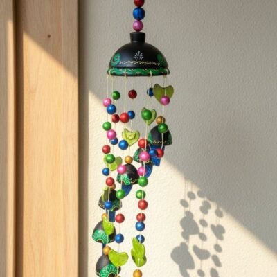 “Handcrafted black and green terracotta wind chime with colourful beads and bells hanging outdoors”