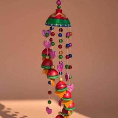 “Vibrant handcrafted terracotta wind chime with colourful bells and beads hanging in sunlight”