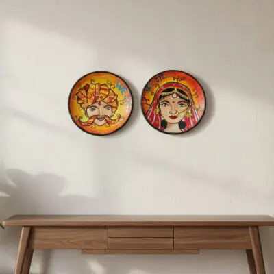 “Hand-painted Rajasthani bride and groom terracotta wall plates with orange-yellow gradient background”