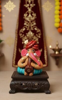 “Handcrafted Reading Ganesha clay idol on wooden chowki – colourful artisan statue for home décor”