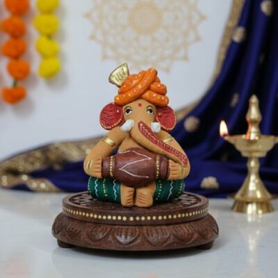 “Handcrafted Reading Ganesha clay idol on wooden chowki – colourful artisan statue for home décor”