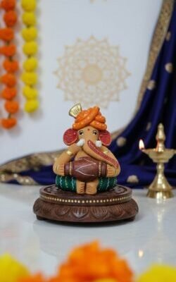 “Handcrafted Reading Ganesha clay idol on wooden chowki – colourful artisan statue for home décor”