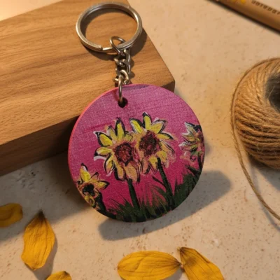 Handmade sunflower MDF round keychain with floral design on pink background