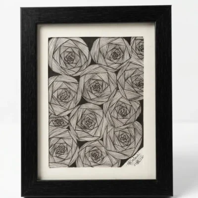 Handmade black and white floral line art framed wall decor on wooden floor with woven mat