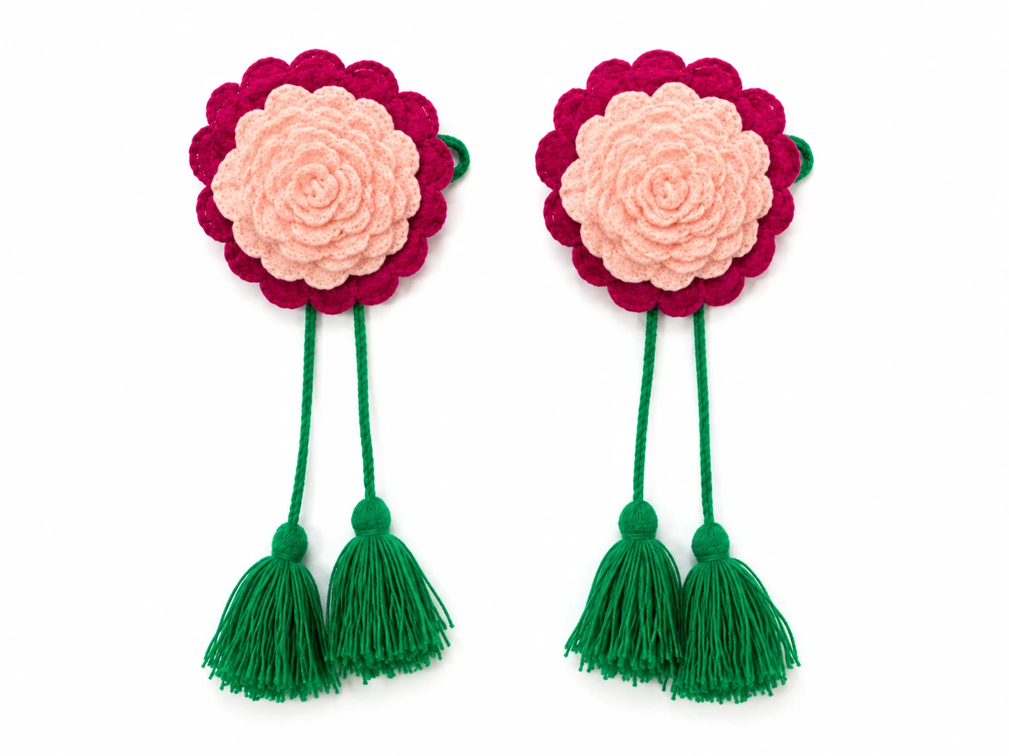 Handmade acrylic yarn crochet flower curtain tieback with decorative tassels attached to a beige curtain.
