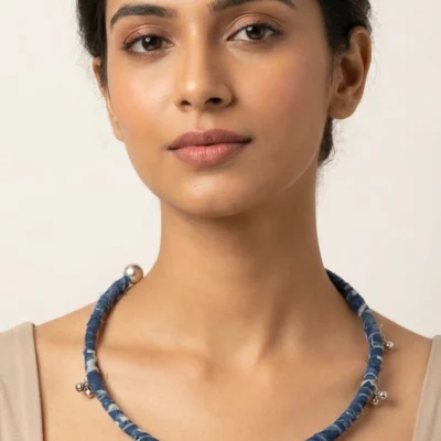 Handmade indigo fabric choker necklace with silver ghungroo charms displayed on model and flat lay background