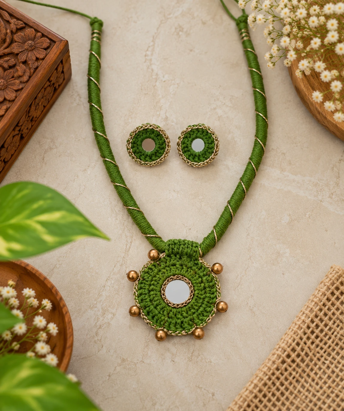 Handmade green crochet necklace with mirror work pendant and matching mirror stud earrings on marble surface